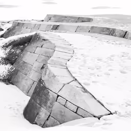 black and white photograph of a snowy bench