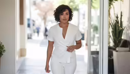 a woman is walking down the street wearing white
