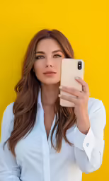 a woman wearing white looking into the camera while holding up her phone