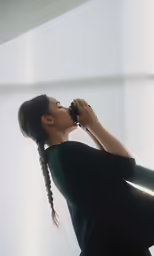 a girl with braids drinking from a black bottle