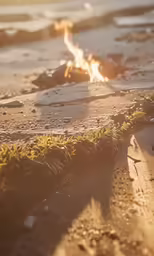 a fire burns on a beach in the sand