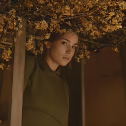 woman with green shirt under a tree in a room