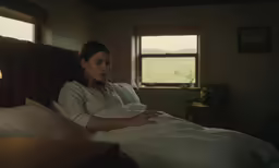 woman laying in bed with arms folded by pillows