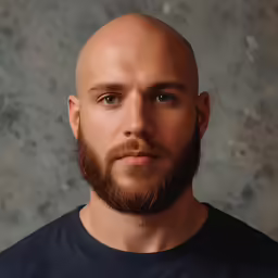 a bald man has a black shirt over his shoulders