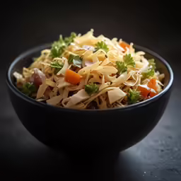 a black bowl filled with noodle salad on a table