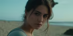 a young woman standing on a beach next to the ocean