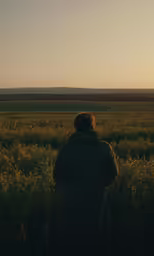 a man standing in a field with a jacket on