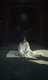 a woman sits on the floor in a dim room