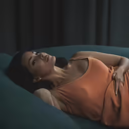 a beautiful woman wearing a tank top laying on a blue couch