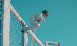 a person wearing a white outfit is standing on the top of a fence
