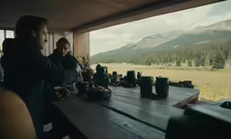 two people sit at a table and a woman looks out of the window