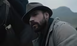the man is sitting near a horse with a hat on