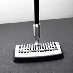 a silver grater with handle on a black table