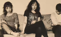 three young women sitting on a couch in black and white