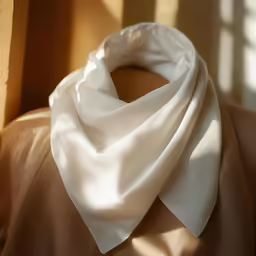 close up of a white scarf hanging from a brown jacket