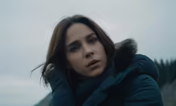 a woman with brown hair wearing a blue jacket and hood