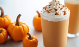 pumpkin spice drink in two cups with whipped cream on top