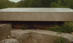 the bottom of a cement bench with trees in the background