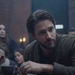 a man sitting in a restaurant with people behind him