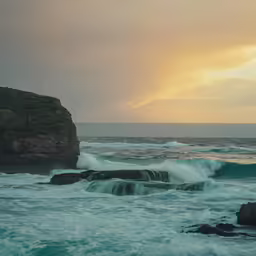 a sunset over an ocean with crashing waves