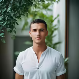 a man in white shirt standing by plants