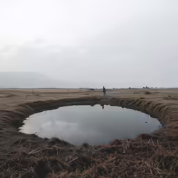 there is a man standing near a puddle on the ground
