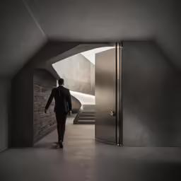 a man is walking in the dark next to a brick building