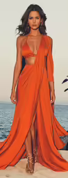 a woman in a long orange dress walking on the beach