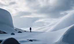 a man is standing in the snow in the mountains