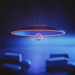 a suspended light with several square shaped pillows on a dark surface