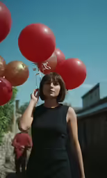 a young lady holding up some red balloons