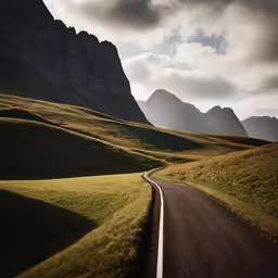 a winding road surrounded by grassy hills
