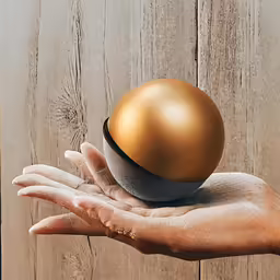 a large golden sphere sitting on top of a black ball