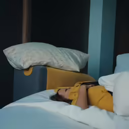 the girl is asleep on the bed next to the pillows