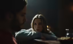 a woman sitting on top of a bar next to a man