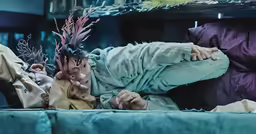 a woman laying on top of a blue couch next to a table