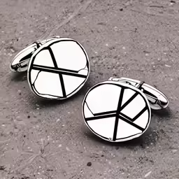 pair of cufflinks on the ground, with a broken letter k