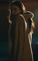 the woman wearing a sweater stands with her hands on her back