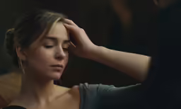 a woman sitting down holding her head to the side