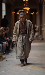 a man in a beige coat is walking down a runway