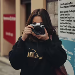 girl in the mirror taking a selfie on a street corner