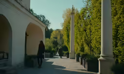 two people walking through a paved pathway between buildings