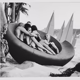 four people are in the pool, the man is sitting on a bench and two of them are being hugged by the women