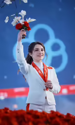 a woman in a white jacket holding flowers