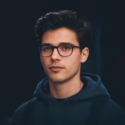 a man wearing black glasses looking directly at the camera