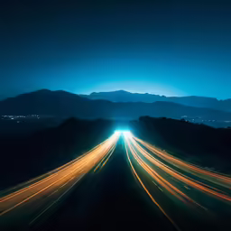 a long exposure shot of the freeway with mountains in the background