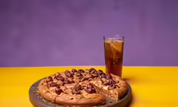 a pizza with nuts is on a plate next to a glass