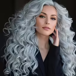 a woman with long wavy gray hair standing and looking at the camera