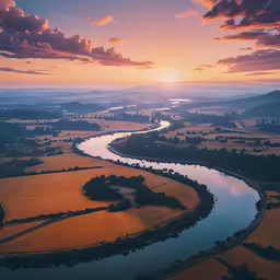 an aerial photo of the sun setting over a river