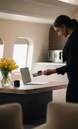 a woman holding a drink near a laptop